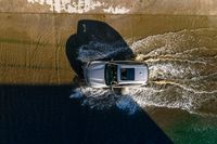 a car driving through the water in the ocean from above the side of a boat