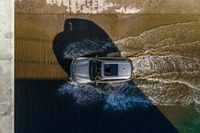 a car driving through the water in the ocean from above the side of a boat