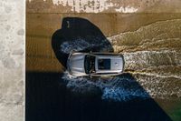 a car driving through the water in the ocean from above the side of a boat