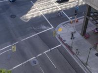 an aerial shot of two cars on a city street at a busy intersection in front of a large building