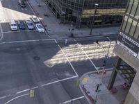 an aerial shot of two cars on a city street at a busy intersection in front of a large building