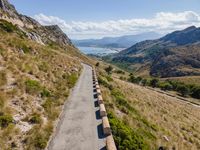 cars driving along a road in mountains area with mountains in the distance and blue sky