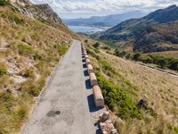 cars driving along a road in mountains area with mountains in the distance and blue sky