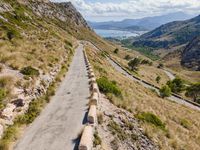 cars driving along a road in mountains area with mountains in the distance and blue sky