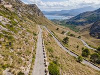 cars driving along a road in mountains area with mountains in the distance and blue sky