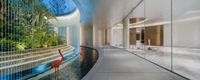 the long hallway leads to a large indoor garden area of an office with a pool next to the curved white building