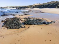 the beach has a group of stones near the water's edge and shore,