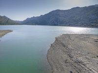 the beach is filled with many footprints as people walk by it near the water and mountain