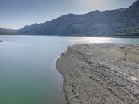 the beach is filled with many footprints as people walk by it near the water and mountain