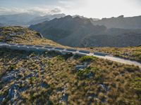 an aerial shot of the road between two mountains with water in the background and sunlight reflecting off of the mountains