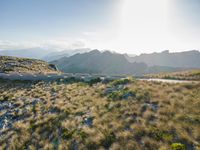 an aerial shot of the road between two mountains with water in the background and sunlight reflecting off of the mountains