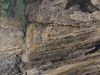 an aerial image shows the rock wall at the top of a cliff, with vegetation growing on top of it