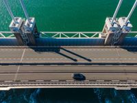 overhead view of a highway bridge going over a body of water with traffic coming down it