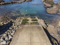 a rocky cliff overlooks a body of water and a dock with benches near it