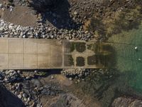 a boat with people in the water on it near rocks and water in front of a pier