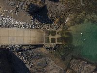 a boat with people in the water on it near rocks and water in front of a pier