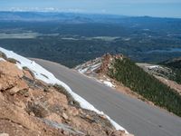 a snow covered road is near a very steep cliff on a clear day the wall is filled with snow and snow