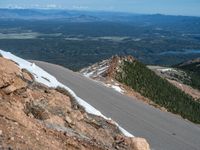 a snow covered road is near a very steep cliff on a clear day the wall is filled with snow and snow