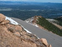 a snow covered road is near a very steep cliff on a clear day the wall is filled with snow and snow