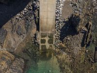 an aerial view of a concrete road tunnel with grass and rocks, with two bicycles parked under a bridge