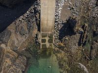 an aerial view of a concrete road tunnel with grass and rocks, with two bicycles parked under a bridge