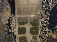 an aerial view of a concrete road tunnel with grass and rocks, with two bicycles parked under a bridge