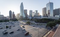 a photo of a car lot and skyline with buildings in the background at sunset as seen from an elevated platform