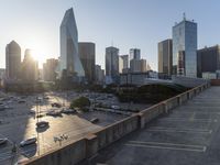 the sun is setting on a view from the top of an building with cars parked in a lot