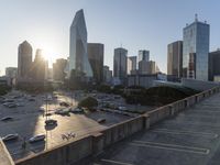 the sun is setting on a view from the top of an building with cars parked in a lot