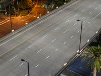 an overhead view of the street, cars and palm trees at night on a city street