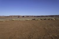 a dry field in an arid area with mountains in the distance under blue skys