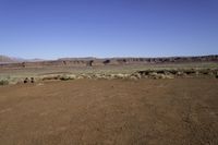 a dry field in an arid area with mountains in the distance under blue skys