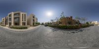 a spherical lens panorama of an empty town street with cars parked on it and people walking in front of the buildings