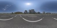 the view of a large empty parking lot from behind a car with buildings in the back ground