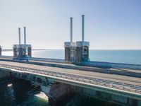 the road goes over an overpass into the ocean in front of an old power plant