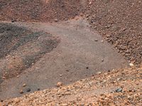 an open dirt field with two different rocks and gravel and a small hill in the background