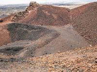 an open dirt field with two different rocks and gravel and a small hill in the background