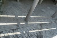 the shadow of a person is walking through a walkway with columns in the background and a green umbrella