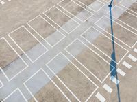 an overhead view looking down at a parking lot with a white crosswalk pattern and a street light