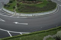 a curved street with several directional arrows on it's sides and grassy areas below