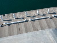 a wooden dock with an overhead view of water and ropes on each end of the dock