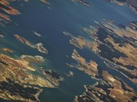 a landscape is seen from the air with a small plane in the distance and blue water on the far side