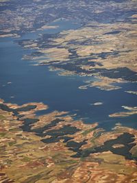 a landscape is seen from the air with a small plane in the distance and blue water on the far side