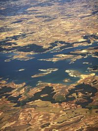 a landscape is seen from the air with a small plane in the distance and blue water on the far side