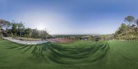 a 360 view of an aerial view of a large field of grass with trees in the background