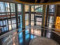 a lobby with marble floors, large windows and several people walking around it from the doors to the ground