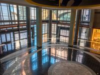 a lobby with marble floors, large windows and several people walking around it from the doors to the ground