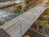 a highway with multiple lanes, in the foreground is the sun setting behind tall buildings