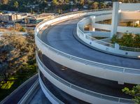 large curved concrete ramp in a modern city with a hillside in the background and trees on the side