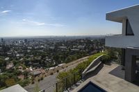 a view from an upstairs floor level home of los angeles skyline and pool with large windows and railings